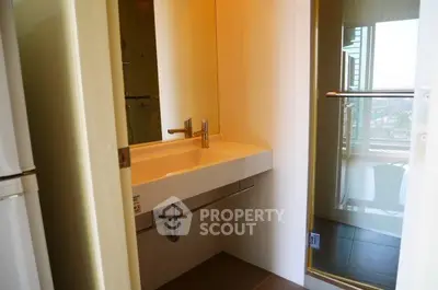 Modern bathroom with sleek sink and glass shower door in a contemporary apartment.
