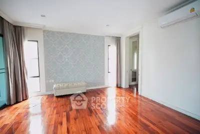 Spacious living room with polished wooden floors and elegant wallpaper