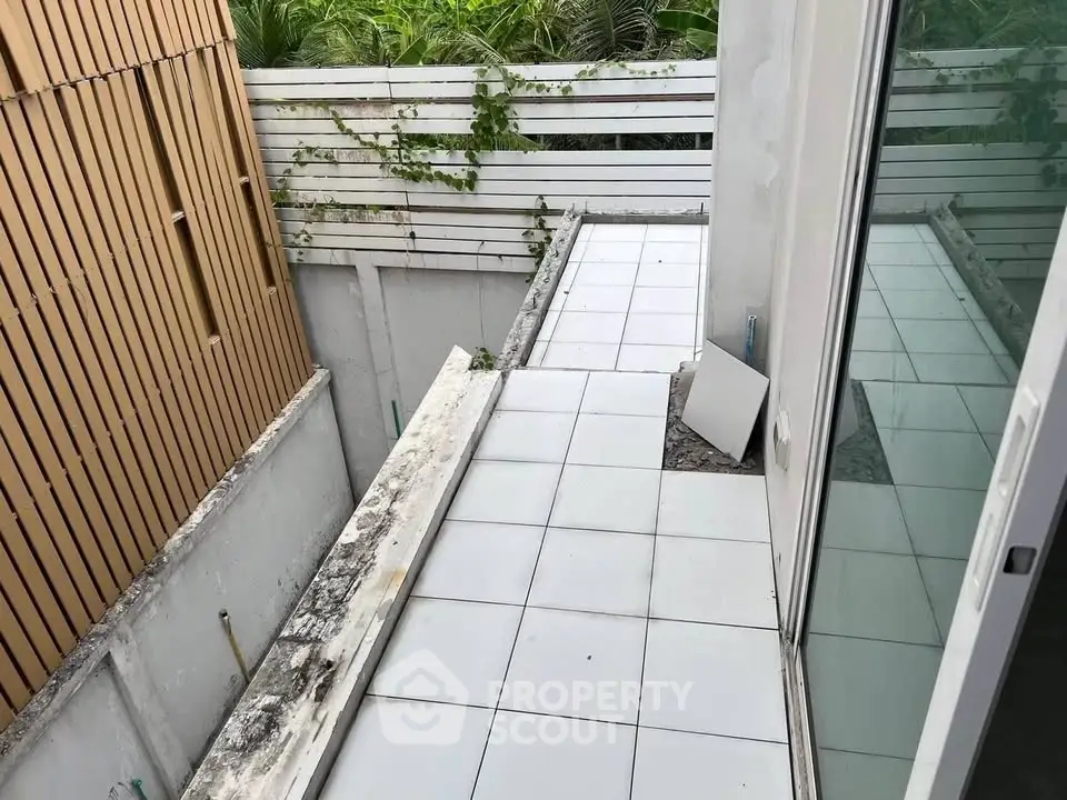 Modern outdoor balcony with tiled flooring and privacy fence, perfect for relaxation.