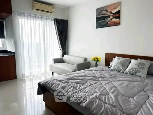 Modern bedroom with cozy bed, stylish sofa, and natural light from large window.
