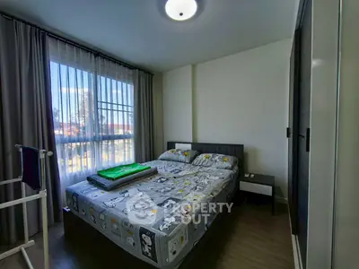 Cozy bedroom with large window and modern decor, perfect for relaxation.