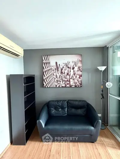 Modern living room with black leather sofa and cityscape artwork, featuring sleek shelving and floor lamp.