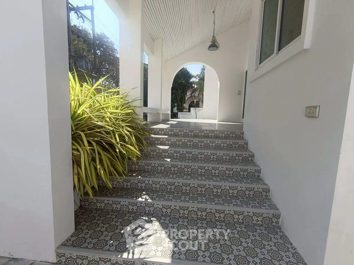 Charming entrance with decorative tiled steps and lush greenery
