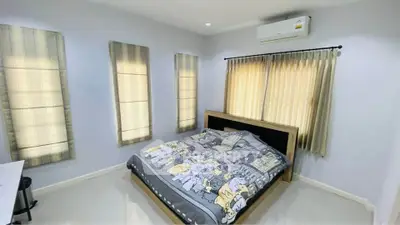 Spacious bedroom with modern decor and ample natural light, featuring a cozy bed and air conditioning.