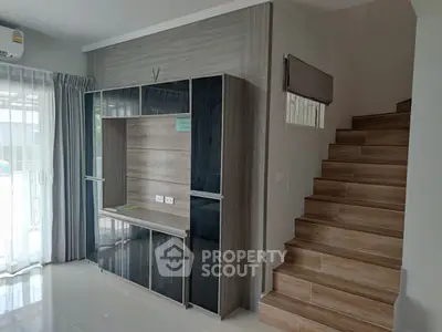 Modern living room with sleek entertainment unit and wooden staircase, perfect for stylish urban living.