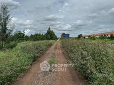 Expansive plot of land with lush greenery and distant residential buildings, perfect for development opportunities.