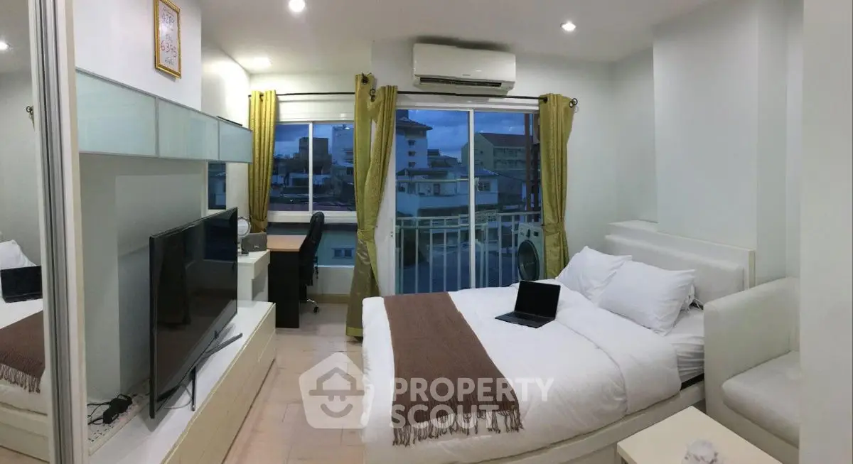 Modern bedroom with large window and city view, featuring a cozy bed and sleek decor.