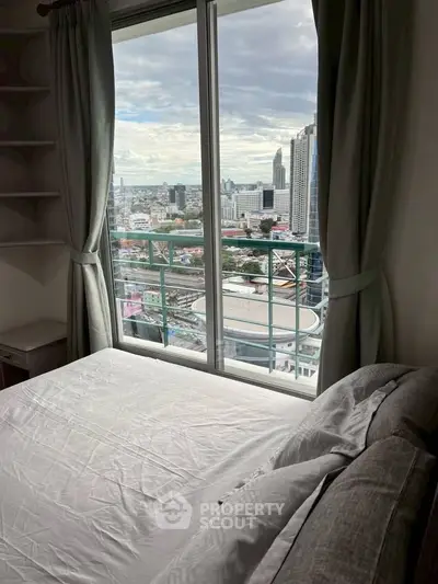 Cozy bedroom with stunning city view from high-rise apartment window.