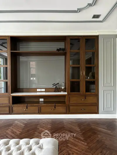 Elegant living room with built-in wooden shelves and herringbone parquet flooring