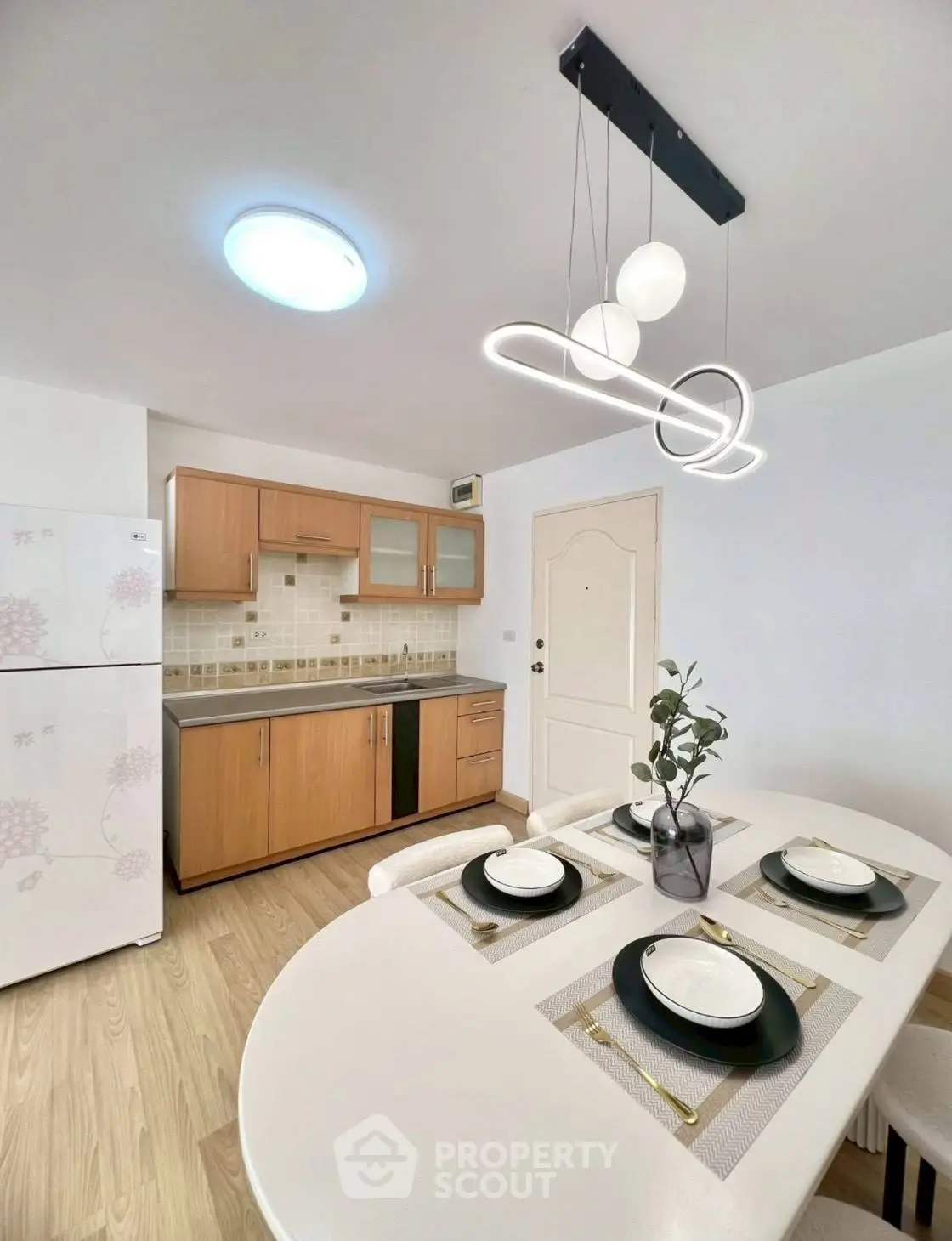 Modern kitchen with dining area, featuring stylish lighting and wooden cabinetry.