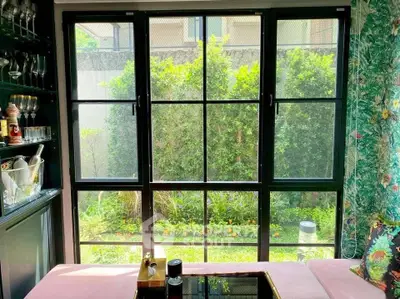 Charming living room with garden view through large windows and elegant decor.