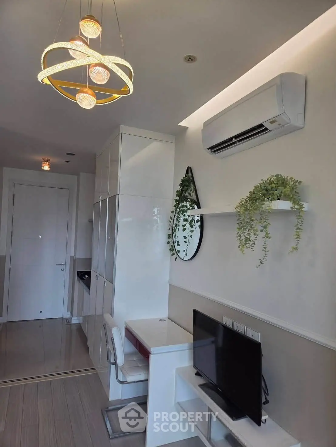 Modern living room with stylish lighting and air conditioning, featuring a compact workspace and TV setup.