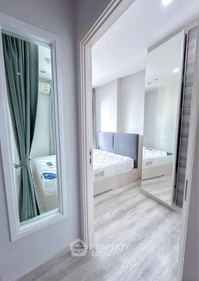 Modern bedroom with mirrored closet and large window, featuring sleek design and ample natural light.