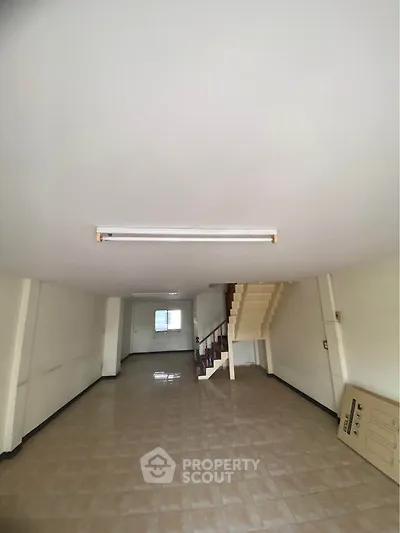 Spacious interior with tiled flooring and staircase, ideal for customization.