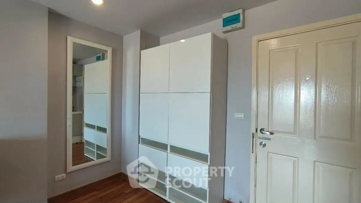 Modern bedroom with sleek white wardrobe and full-length mirror