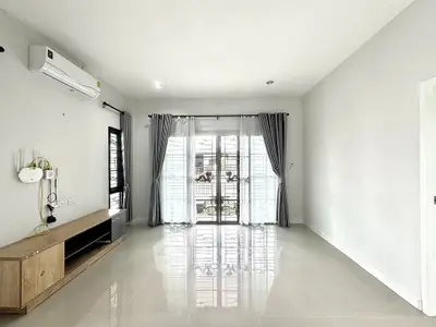 Spacious empty living room with large windows and modern air conditioning unit.