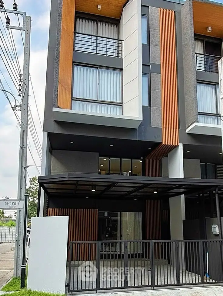 Modern multi-story building with unique facade design and gated entrance.