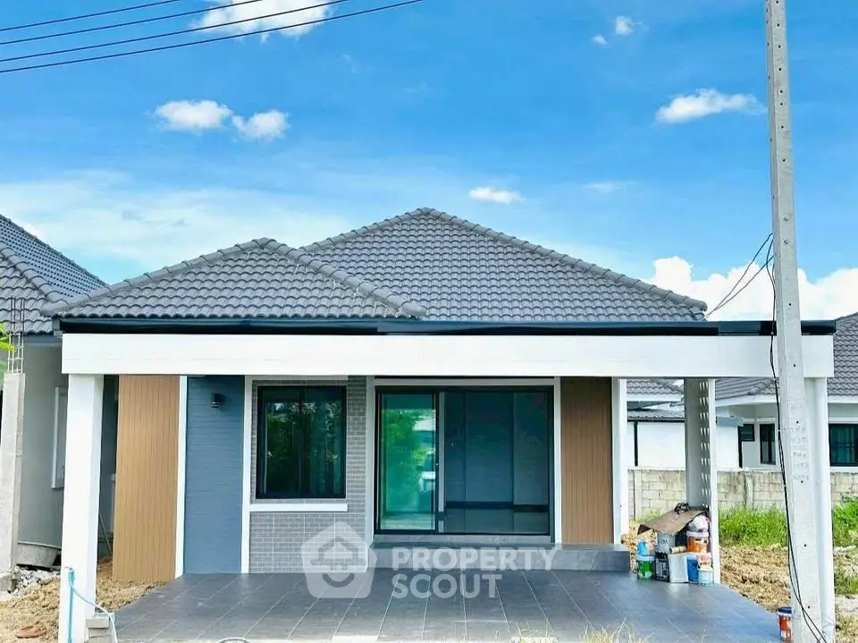 Charming single-story house with modern design and spacious front yard under a clear blue sky.