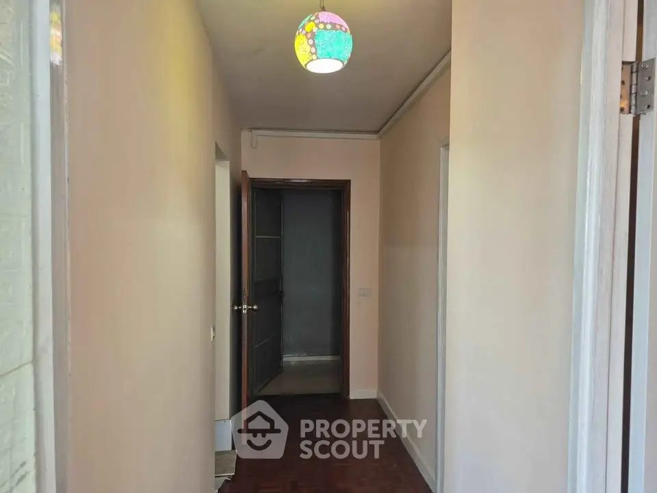 Charming hallway with wooden flooring and colorful ceiling light in cozy apartment.