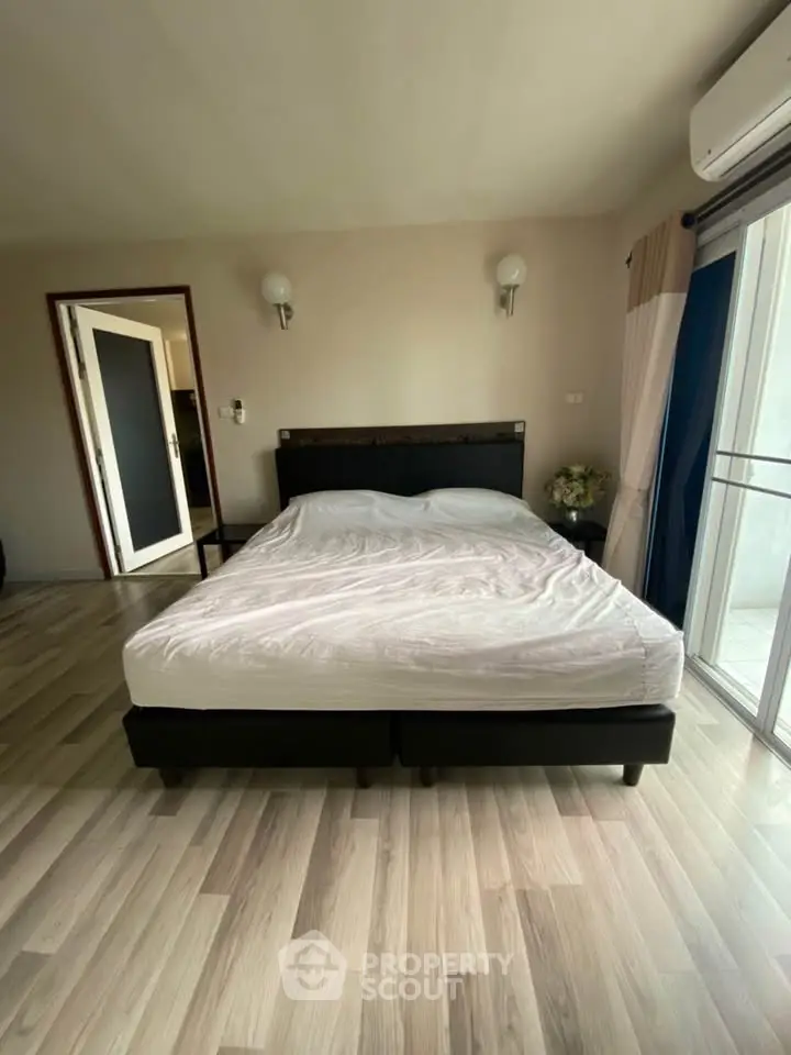 Spacious bedroom with modern decor and natural light from large window.