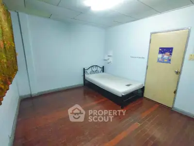 Minimalist bedroom with single bed and wooden flooring, ideal for cozy living.