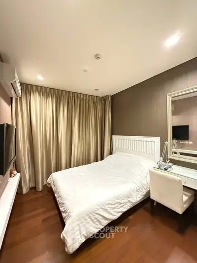 Elegant bedroom with wooden flooring, cozy bed, and stylish decor in a modern apartment.