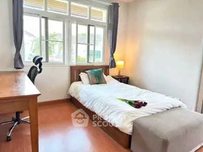 Cozy bedroom with wooden flooring, single bed, and large window for natural light.