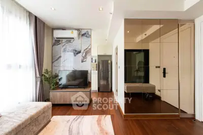Modern living room with hardwood floors, mirrored wall, and sleek furniture.