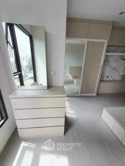Modern bedroom with large windows and sleek storage solutions in urban apartment