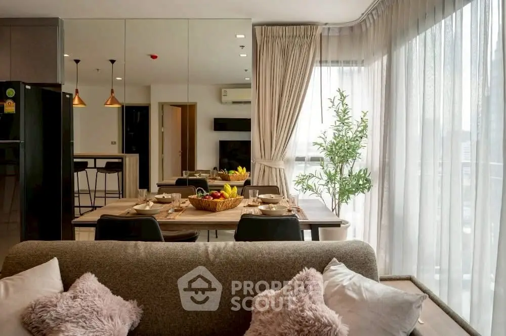 Modern living room with dining area and large windows offering natural light.