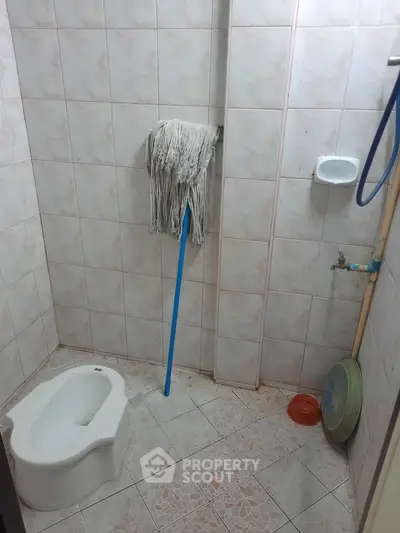 Compact bathroom with squat toilet and cleaning mop