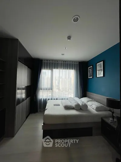Modern bedroom with city view, featuring stylish decor and ample natural light.
