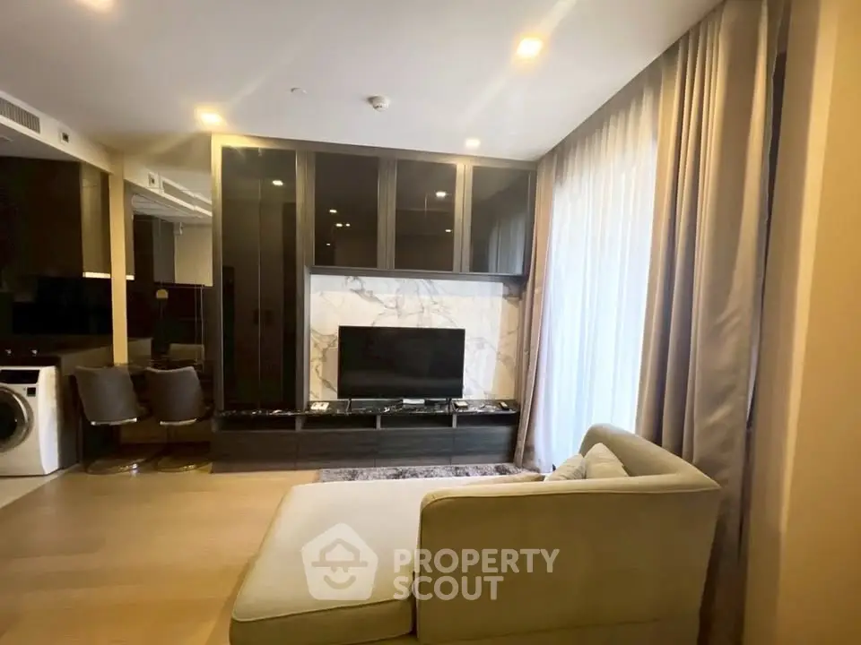 Luxurious living room with modern decor and natural light, featuring a sleek TV setup and comfortable seating.