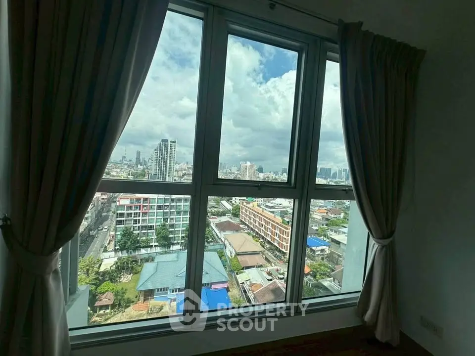 Stunning cityscape view from a high-rise apartment window with elegant curtains.