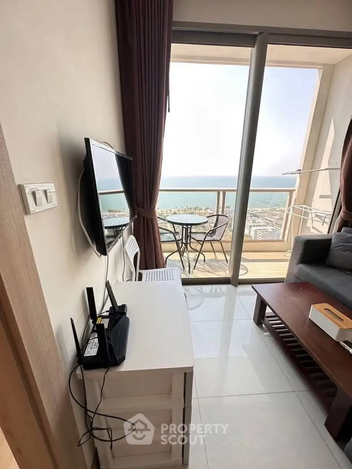 Modern living room with stunning sea view from balcony, featuring sleek furniture and natural light.
