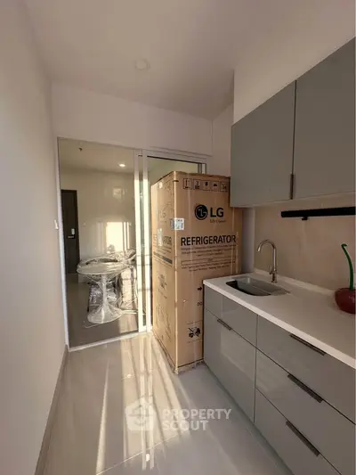 Modern kitchen with sleek cabinetry and new LG refrigerator in a bright apartment.