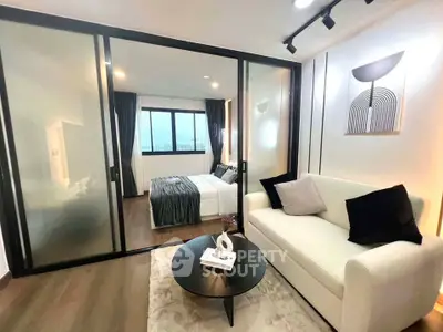 Modern apartment with sliding glass doors separating living room and bedroom, featuring stylish decor.