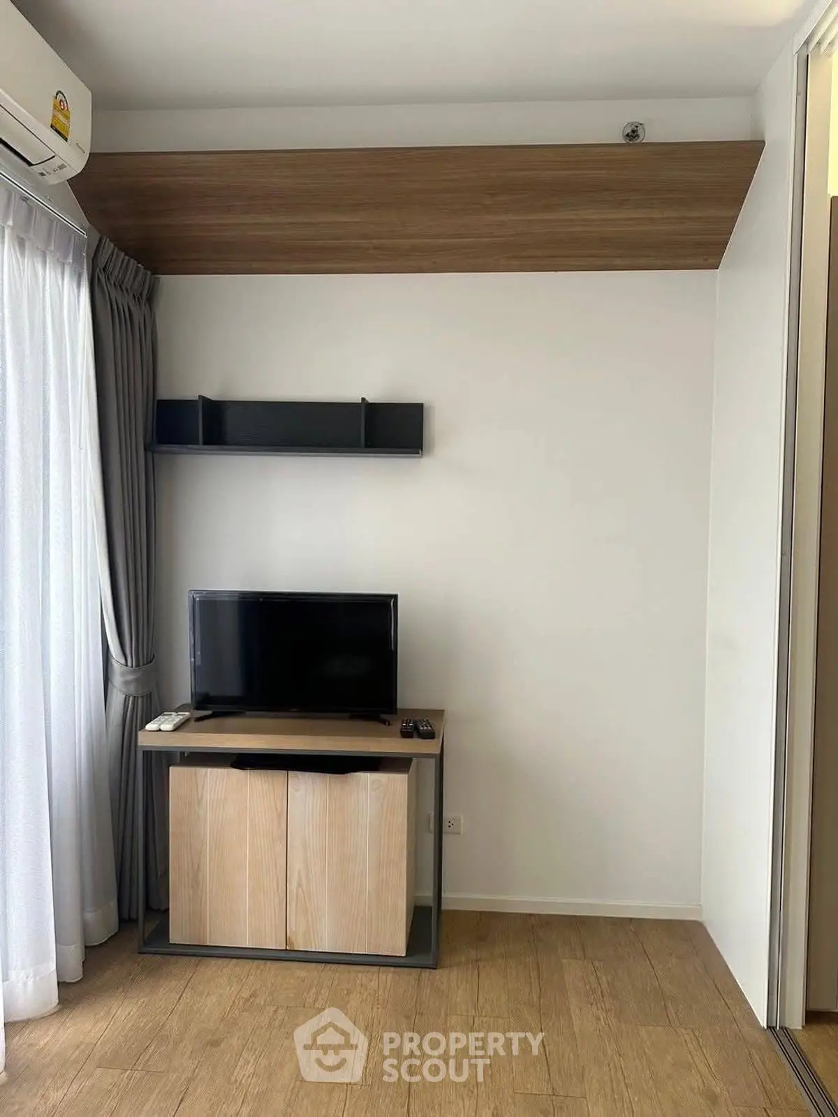 Modern living room with sleek TV stand and wall-mounted shelf, featuring wooden flooring and elegant curtains.