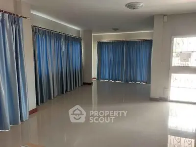 Spacious living room with large windows and blue curtains, perfect for natural light.