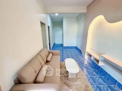 Modern living room with blue tiled floor and cozy beige sofa, featuring unique wall lighting.