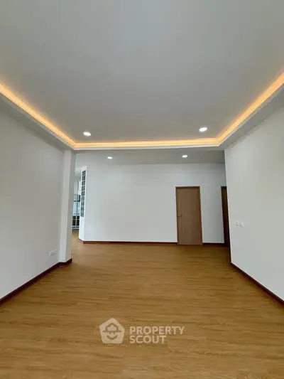 Spacious modern living room with elegant recessed lighting and wooden flooring.