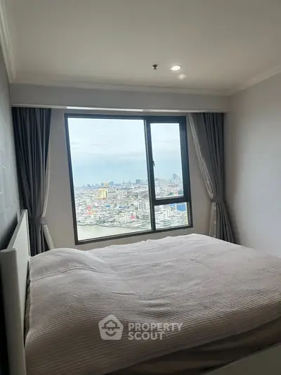 Spacious bedroom with stunning city view from large window, perfect for urban living.