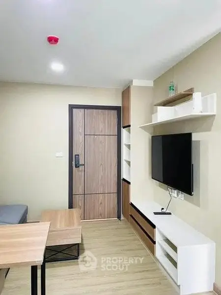 Modern living room with sleek furniture and wall-mounted TV in a cozy apartment.