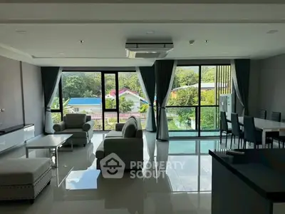 Spacious living room with large windows and garden view, featuring modern furniture and elegant decor.