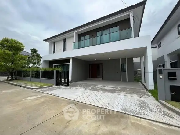 Modern two-story house with spacious driveway and sleek balcony design.