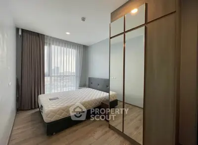 Modern bedroom with sleek mirrored wardrobe and large window view.