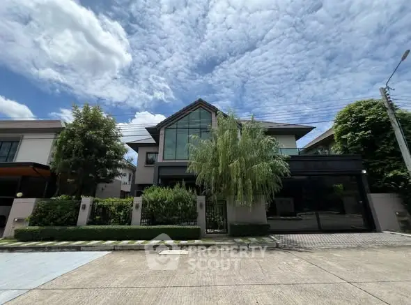 Stunning modern house exterior with lush greenery and expansive windows under a vibrant sky.