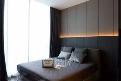 Modern bedroom with sleek design and ambient lighting, featuring a cozy bed and large window.