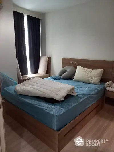 Cozy bedroom with a large bed, wooden headboard, and elegant dark curtains, offering a tranquil retreat in a modern home.