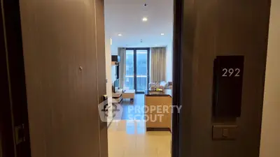 Luxurious apartment entrance with modern living room and large windows.